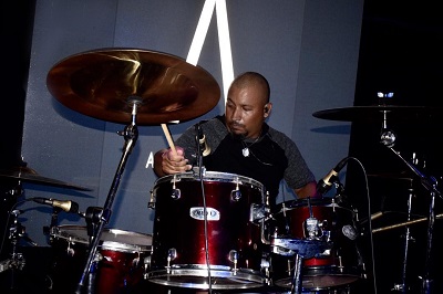 Palco com iluminação e o logo da banda Artificial aceso ao fundo.