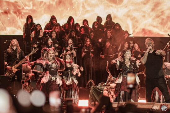 Banda Saurom se apresentando ao vivo com iluminação intensa e público ao fundo